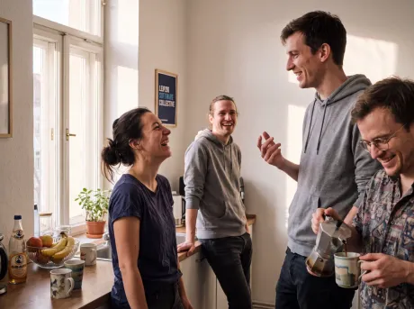 Das RookUp-Team lacht gemeinsam bei einem Kaffee im Leipziger Büro